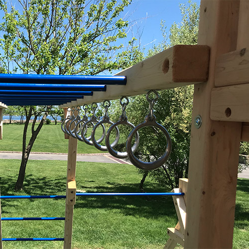 Wooden swing set monkey bars with steel hand hold rings.