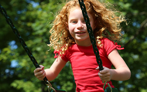 Girl swinging on a wooden play set. 