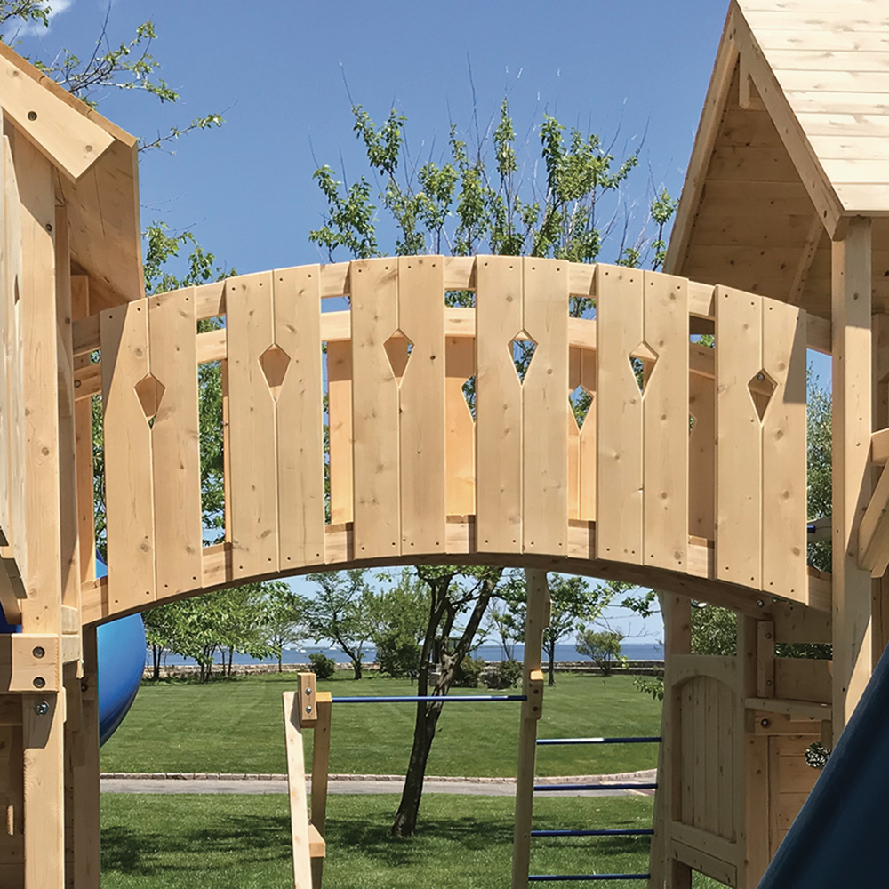 A arched bridge connecting two cedar swing set forts.