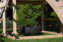 Triumph Play System's Kelton Climber cedar swing 360 degree tire swing under the fort.
